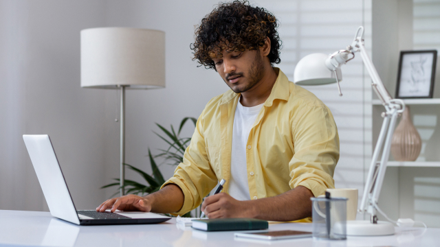 A man is taking notes from analyzing his online course performance and is ready to launch a new course
